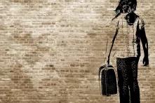 Graffiti/shadow on a brickwall showing a refugee girl walking with her suitcaseGraffiti/shadow on a brickwall showing a refugee girl walking with her suitcaseGraffiti/shadow on a brickwall showing a refugee girl walking with her suitcase